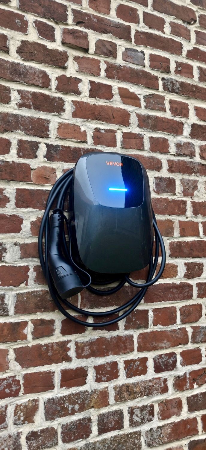 Borne de recharge pour véhicule électrique installée sur un mur, avec câble de recharge enroulé
