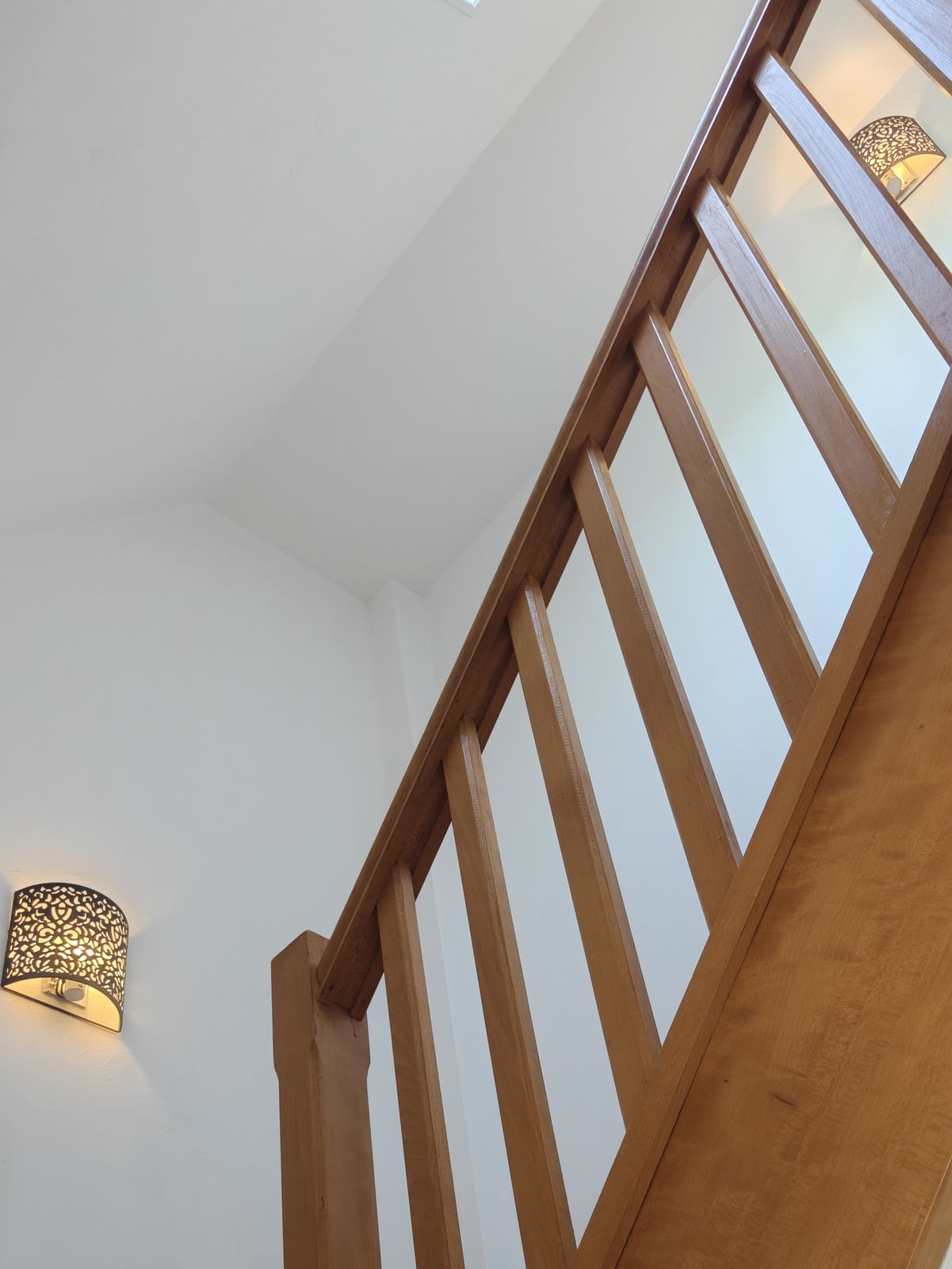 Appliques murales décoratives à motif ajouré, éclairant une cage d'escalier en bois