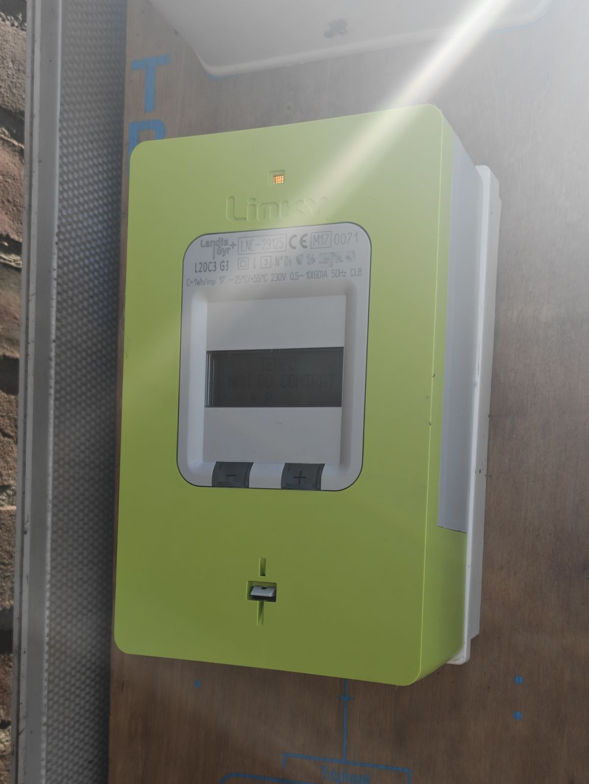Compteur Linky vert affichant l'option tarifaire Tempo, fixé sur un mur