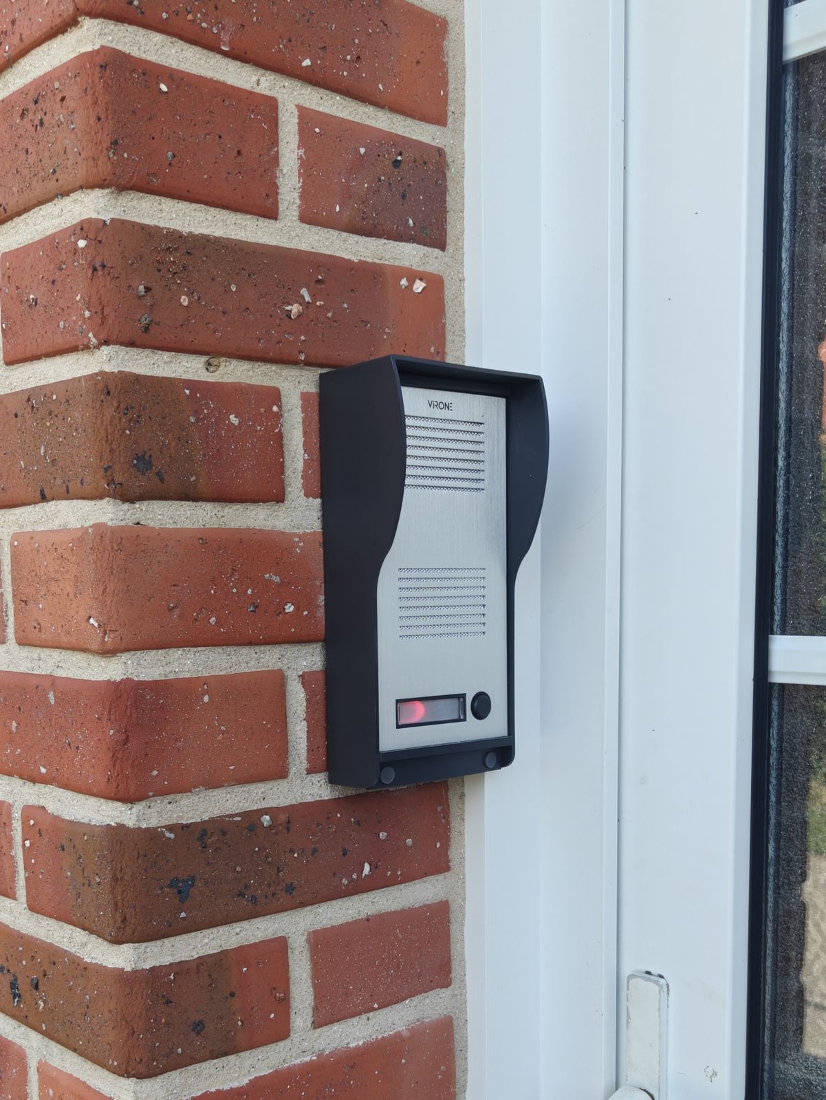 Platine de rue d'un interphone installée en façade de brique