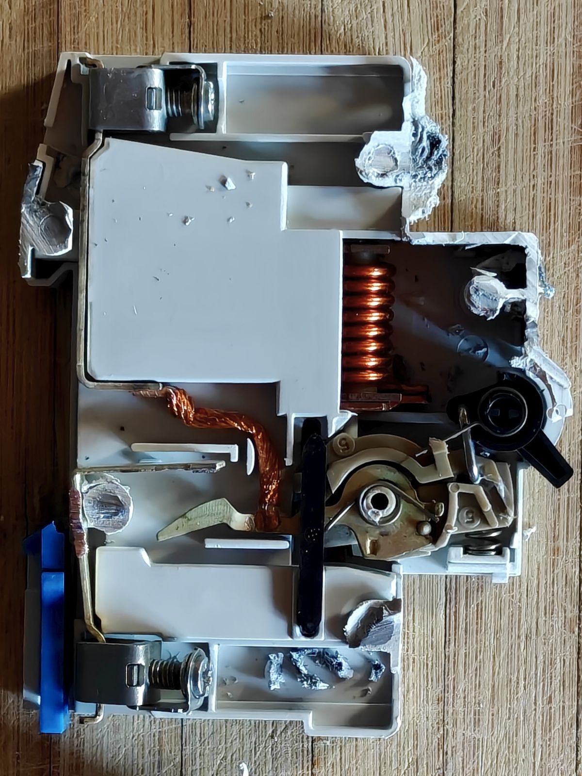 Mécanisme interne d'un disjoncteur électrique démonté, montrant la bobine et le système de déclenchement thermique